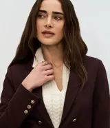 Blazer femenino de sastrería confeccionado en tejido Punto Roma, con cuello solapa, cierre frontal con ganchos y botones decorativos dorados con escudo grabado.