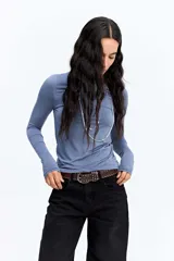 Remera de manga larga ajustada al cuerpo, confeccionada en tejido suave y elástico. Presenta un diseño minimalista con cuello redondo, ideal como prenda base o protagonista de diversos looks.