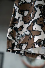 Short deportivo con estampado abstracto en tonos marrones y blancos, con aberturas laterales.