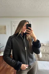 Campera reversible de corte recto y largo a la cadera. Un lado presenta un acabado de napa negra, mientras que el otro lado está confeccionado en piel sintética de color azul noche, extremadamente suave al tacto. Cuenta con mangas largas y un diseño versátil y elegante.