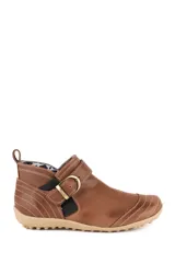 Bota baja de cuero color marrón, estilo botín con elásticos laterales y tira con hebilla metálica ajustable. Cuenta con costuras decorativas pespunteadas y suela de goma con relieve.