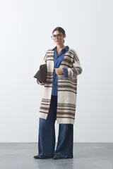 Cardigan largo de tejido de punto con diseño de rayas horizontales en tonos beige, marrón y blanco. Presenta una silueta relajada, mangas largas y frente abierto.