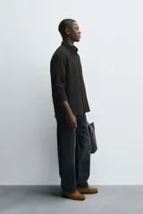 Camisa de corte regular fit confeccionada en tejido de algodón con textura de cuadrillé. Presenta cuello solapa, manga larga con puños abotonados y cierre frontal mediante botonadura.