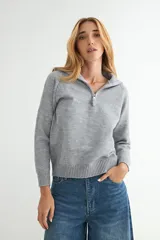 Buzo de punto gris con cuello polo y cierre frontal parcial, de manga larga y diseño holgado con puños y ruedo acanalados.
