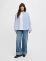 Camisa de popelín blanca de manga larga con cuello clásico y cierre frontal de botones ocultos, de ajuste relajado y puños anchos.