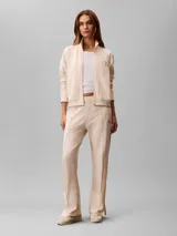 Campera de felpa con cierre de Calvin Klein, color beige, con cuello alto, bolsillos laterales, puños y bajo elásticos, y logo bordado en el pecho.