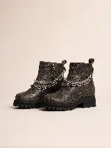 Botas cortas de cuero marrón con textura envejecida, suela track negra con plataforma y taco bajo. Presentan un detalle de tres cadenas metálicas plateadas removibles alrededor del tobillo y cierre lateral interno.