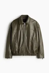 Cazadora estilo bomber en tejido revestido color verde militar, con cuello clásico, cierre frontal de cremallera metálica, bolsillos laterales y elástico fruncido en el bajo y los puños.