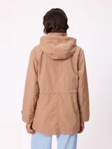 Rompevientos negro con capucha ajustable mediante cordones, cierre frontal de cremallera y ajuste en la cintura con cordón. Presenta logo de la marca bordado en el pecho y puños con detalle de botón.