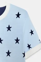 Chaqueta de punto celeste con estampado de estrellas en azul marino, cuello redondo, manga corta y cierre frontal con botones.