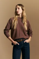 Polera de tejido de punto color marrón, con cuello alto y diseño de líneas verticales en el frente que aportan estructura. Presenta un calce relajado y mangas largas con puños ajustados.