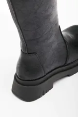 Botas negras de ecocuero con cierre lateral, caña alta y suela track.