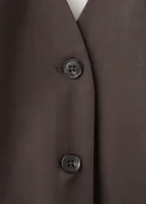 Chaleco marrón de lino y algodón, con diseño entallado, cuello halter, escote en pico, sin mangas, espalda abierta, bolsillos de ribete delanteros y cierre frontal de botones.