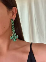 Aro colgante de diseño geométrico, compuesto por una base rectangular y una pieza inferior en forma de cruz, ambos recubiertos con mostacillas en tonos verdes y detalles metálicos.