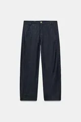 Pantalón de tiro medio con corte barrel, bolsillos laterales ocultos en costura y falsos bolsillos de vivo en la parte trasera. Presenta costuras laterales torcidas y cierre frontal con cremallera y botón.