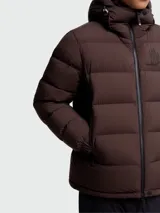 Campera puffer de esquí Moncler Grenoble modelo Isorno, color marrón oscuro, con capucha ajustable, cierre frontal, bolsillos laterales y puños con aberturas para pulgares.