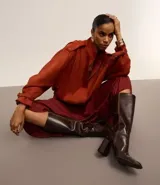 Falda midi evasé color borgoña de poliéster satinado, con cierre trasero invisible, volado en la cadera y ruedo fruncido.