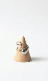 Anillo ajustable de acero color plateado, con diseño abierto y detalle de gota voluminosa en un extremo.