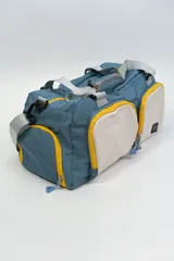 Bolso deportivo color rosa con detalles en beige y gris. Tiene doble asa de mano y correa de hombro ajustable. Cuenta con dos bolsillos frontales con cierre y logo de la marca en la esquina inferior derecha.