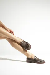 Mocasín de cuero marrón con diseño clásico, detalle de antifaz en el empeine y costuras visibles en la puntera.