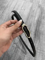 Cinto fino de cuero negro con hebilla irregular plateada.