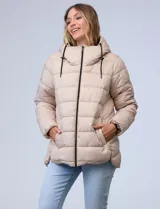 Campera puffer beige con capitonado horizontal, cuello alto envolvente y capucha ajustable con cordones negros. El interior del cuello tiene textura aterciopelada en contraste. Cuenta con cierre frontal completo, bolsillos laterales y un corte ligeramente más largo en la parte posterior con aberturas laterales redondeadas.