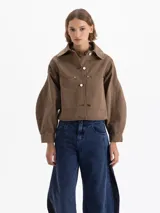 Chaqueta de gabardina color marrón, con cuello camisero, cierre frontal con botones metálicos, bolsillos frontales y mangas abullonadas con puños rectos.