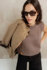 Chaleco tejido de punto sin mangas, con cuello redondo y terminaciones acanaladas. Presenta un diseño clásico y minimalista con un pequeño detalle de etiqueta lateral.