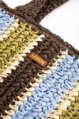 Bolso tipo shopper tejido de papel con diseño de rayas verticales en tonos marrón, celeste, verde oliva y beige. Cuenta con doble asa de hombro y detalle de etiqueta de marca en el frente.