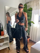 Pantalón negro de cuero sintético con flecos en los laterales.