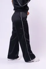 Pantalon deportivo de corte recto y holgado, color negro con una línea lateral blanca. Confeccionado en tela satinada con cintura elástica.