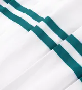 Minifalda de tenis blanca con tableado y cintura elástica. Presenta dos líneas horizontales verdes en el ruedo y logo de la marca en la cintura.