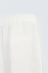 Pantalón de corte relajado confeccionado en tejido de lino. Presenta cintura elástica, bolsillos frontales, bolsillo trasero de vivo y cierre frontal con cremallera y botón.
