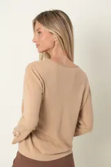 Buzo marrón de punto con cuello redondo y mangas largas. Detalle de puño abierto con moña y perla.