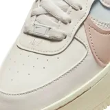 Championes Nike Air Force 1 Shadow, modelo de plataforma con diseño en capas. Presenta una base en tono crema con detalles en rosa pastel y celeste en los swooshes laterales. Suela de goma con tecnología Air para mayor amortiguación.