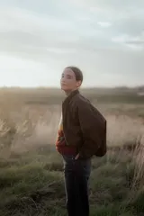 Campera tipo bomber color marrón oscuro, con cierre frontal, cuello redondo y diseño holgado.