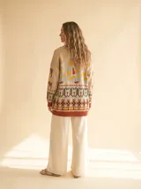 Cardigan de tejido grueso con cuello shawl, estampado tribal en tonos crema, rojo arcilla y negro, con cierre frontal de botones.