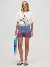 Short de algodón tejido con patrón a rombos, con pretina elástica combinada en tonos turquesa y morado/bordó. Presenta un efecto degradado de color desde el turquesa en la cintura hasta el bordó en el ruedo.