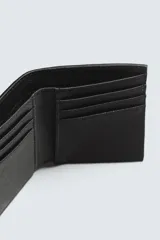 Tarjetero vertical de cuero sintético color verde oliva con textura granulada. Tiene un compartimento principal para billetes y seis ranuras para tarjetas.