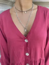 Collar plateado de doble cadena, una corta de esferas pequeñas y una larga de eslabones grandes, con dije de candado plateado.