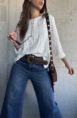 Blusa oversize de color blanco con diseño romántico y bohemio, confeccionada con detalles de encaje y botones forrados en el frente. Cuenta con mangas largas.