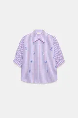 Camisa de cuello solapa y mangas cortas abullonadas, con diseño de rayas verticales en tonos rosados y celestes, decorada con lentejuelas bordadas.