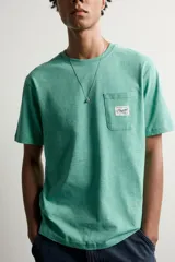 Camiseta regular fit de color verde, con cuello redondo, manga corta y un bolsillo de parche en el pecho con detalle de etiqueta estampada.