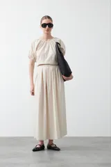 Falda larga plisada color marrón, de silueta amplia y caída fluida.