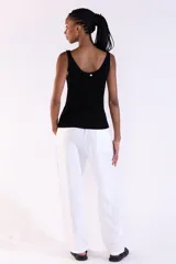 Musculosa de punto canalé color negro, tejida con hilos metálicos de lurex que aportan un brillo sutil, con escote bote y tirantes anchos.