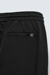 Pantalón tipo jogger de corte slim fit, confeccionado en tejido de algodón con elasticidad. Presenta cintura elástica ajustable con cordón, bolsillos frontales, bolsillos traseros de vivo y bajos con puños elásticos.