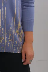 Sweater de tejido de punto color azul jean, con escote en V y manga larga. Presenta un diseño estampado con líneas verticales y salpicaduras en color dorado.