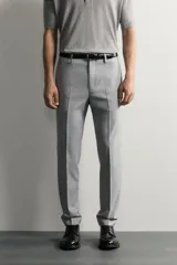Pantalón de traje slim fit color gris, con bolsillos frontales, bolsillos traseros de doble vivo, trabillas para cinturón y cierre frontal con cremallera y botón.