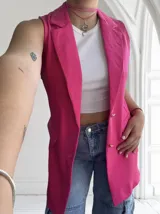 Chaleco fucsia sin mangas con solapas y cierre con botones dorados.
