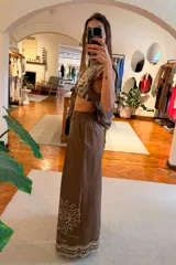 Pantalon de pierna ancha y tiro alto color marron, con bordado en contraste que recorre el ruedo y detalles en calado.